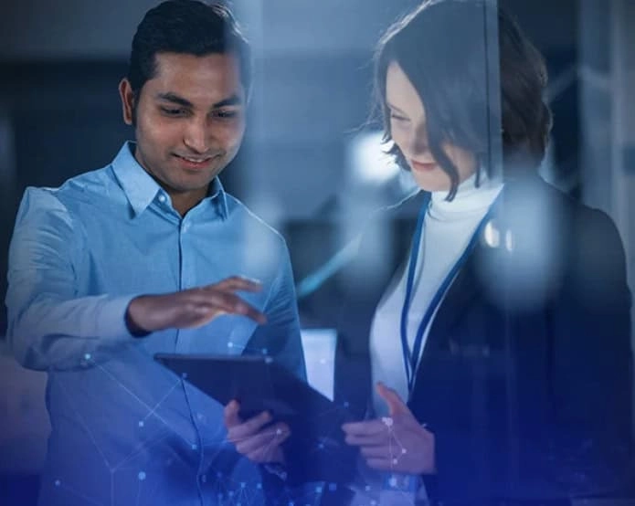 Muškarac i žena u poslovnom okruženju gledaju tablet i razgovaraju