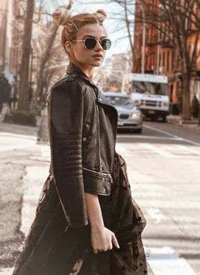 Devojka na ulici sa sunčanim naočarima u haljini i kožnoj jakni